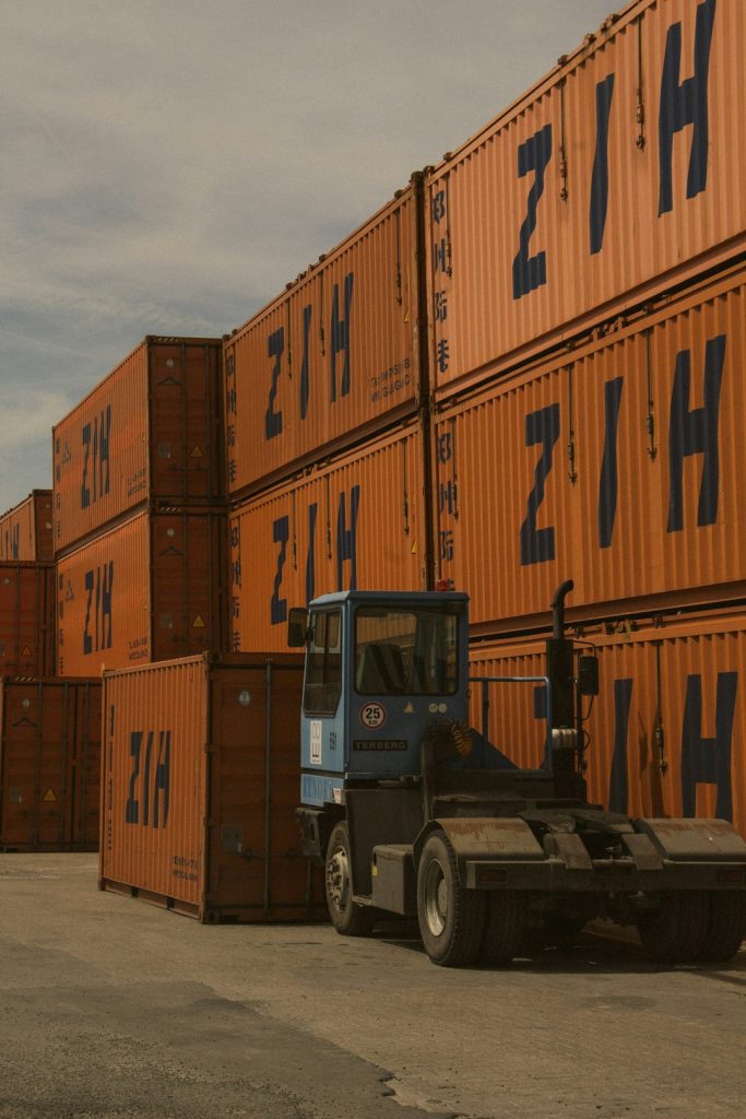 a-forklift-parked-in-front-of-a-large-stack-of-shipping-containers-0dhrdqk2dwo